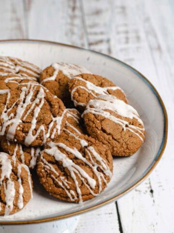 Chai ginger molasses cookies with vanilla cream icing on wire rack.