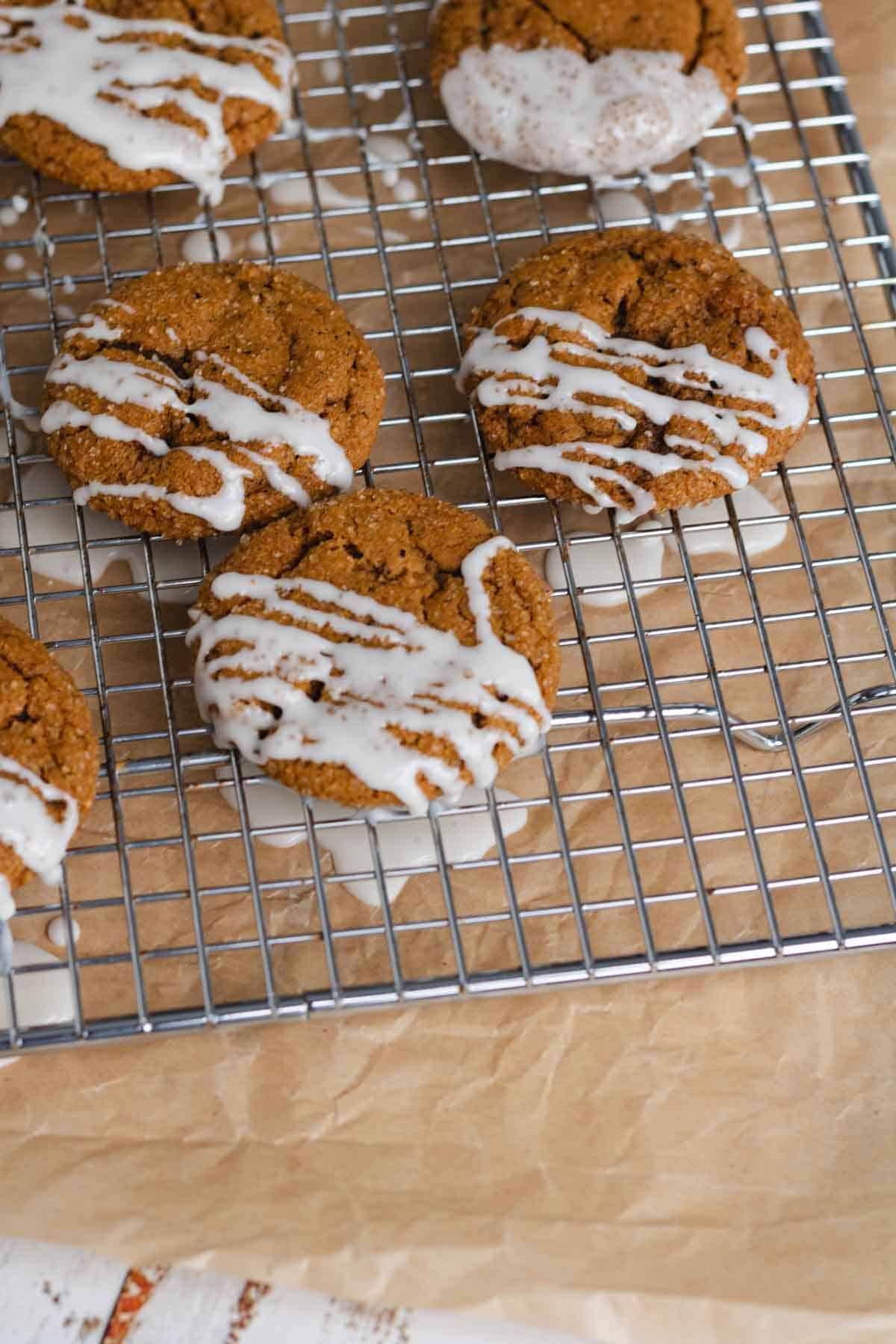chai ginger cookies drizzeled with vanilla glaze on a wire rack over parchment paper