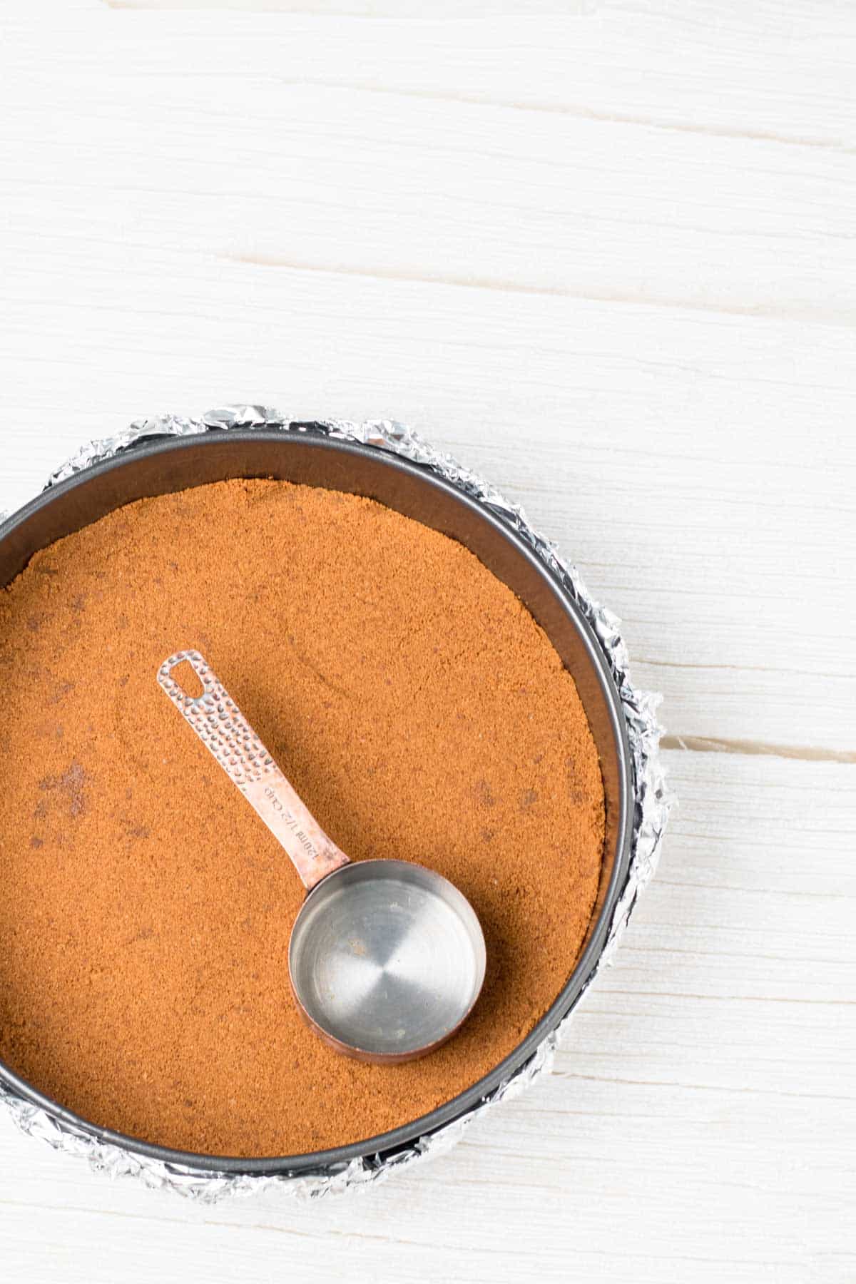 use a dry measuring cup to press the cookie crust into the bottom of a spring form pan for a flat and even cheesecake bottom