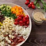 chopped italian salad with ingredients on a serving platter ready to be tossed, salami, provolone, tomatoes