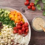 Colorful Italian lunch salad with cherry tomatoes, cucumbers, and herbs on a wooden table.