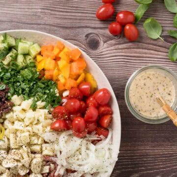 Colorful Italian lunch salad with cherry tomatoes, cucumbers, and herbs on a wooden table.