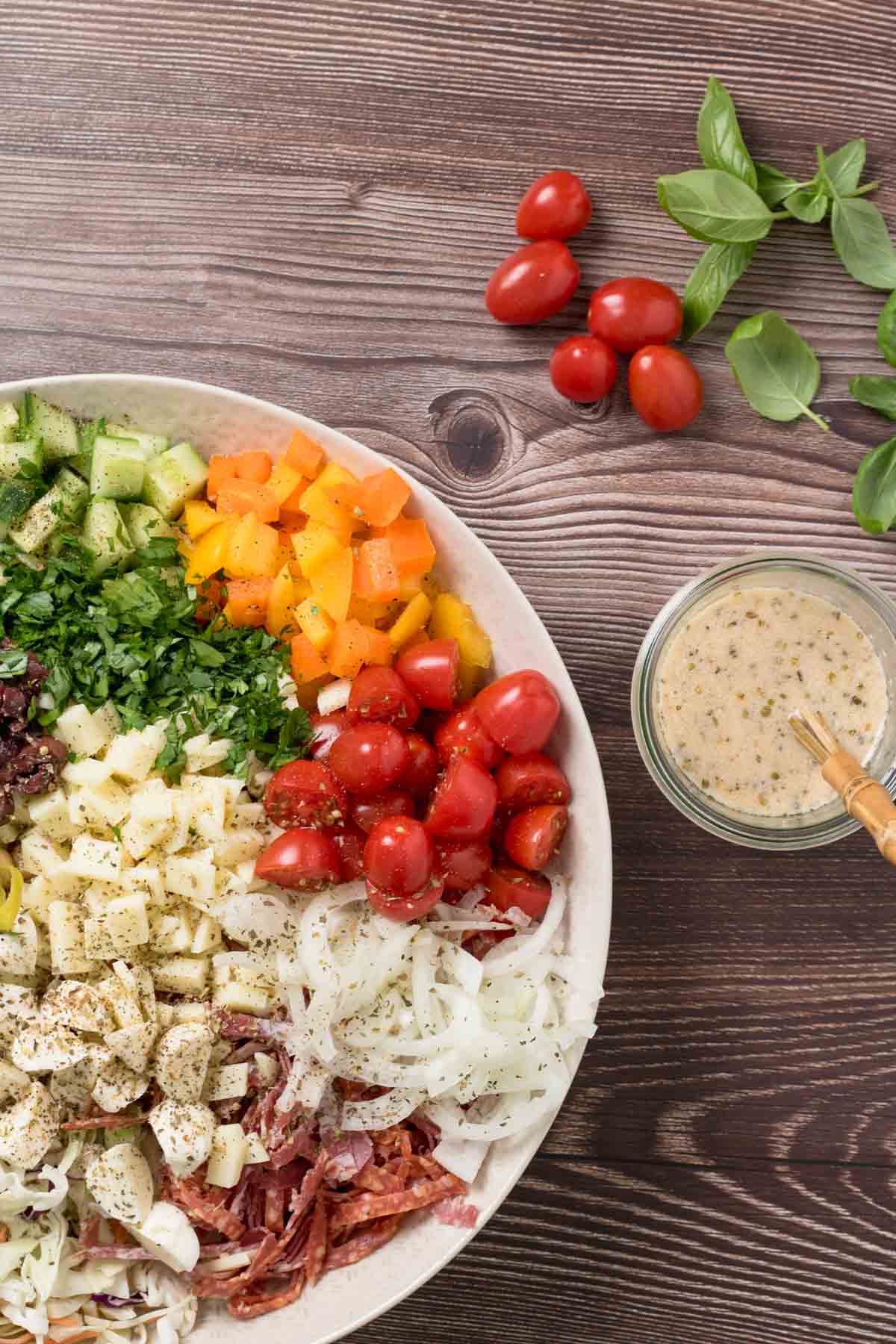 Colorful Italian lunch salad with cherry tomatoes, cucumbers, and herbs on a wooden table.